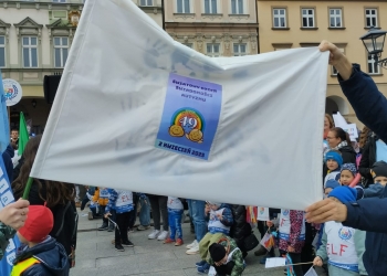 uczestnicy marszu trzymają w rękach flagę okolicznościową.