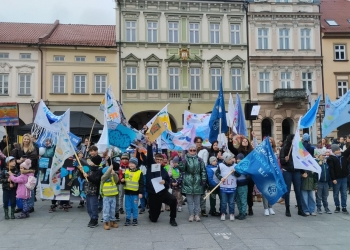 Wspólna fotografia uczestników marszu, którzy trzymaja w rękach kolorowe flagi, choragiewki i inne akcesoria związane z tematyką marszu.