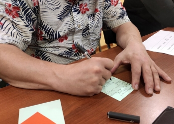 Uczestnik spotkania zapisujący tekst na kolorowej kartce.