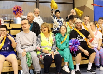 Publiczność dopingująca swoje drużyny. W dłoniach trzymane sa kolorowe pompony.