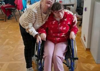 Uczestniczki spotkania pozują do zdjęcia. Jedna z osób korzysta z wózka.