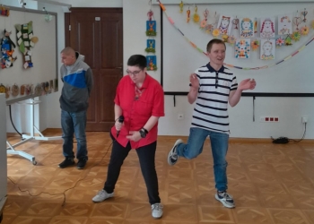 Dwie osoby tańczą na parkiecie, w tle jedna osoba ogląda wystawę.