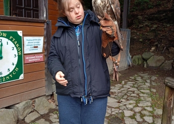Uczestniczka wycieczki pozuje do zdjęcia, trzymając na ręce sokoła. 