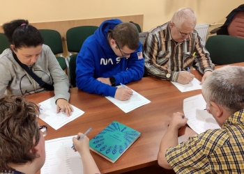 Uczestnicy spotkania piszą na kartkach nowe słowa z rozsypanych liter. 