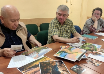 Uczestnicy siedzący przy stole wybierają z kolorowych obrazków te, które będa przydatne do wspólnego opowiadania.