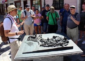 Przewodnik opowiada historię starówki lubelskiej stojacym dookoła uczestnikom wycieczki.