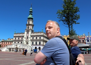 Uczestnicy wycieczki odpoczywający na Rynku w zamościu. W tle ratusz.