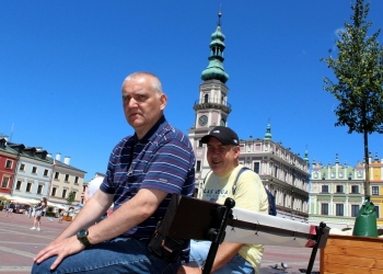 Uczestnicy wycieczki odpoczywający na Rynku w zamościu. W tle ratusz.