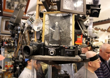 Zwiedzający ogladają zabytkowy sprzęt fotograficzny.