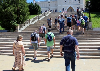 Uczestnicy wycieczki wchodzą po schodach prowadzących do zamku lubelskiego.