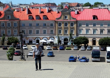 Uczestnik wycieczki pozuje do zdjęcia na tle kamienic lubelskich.