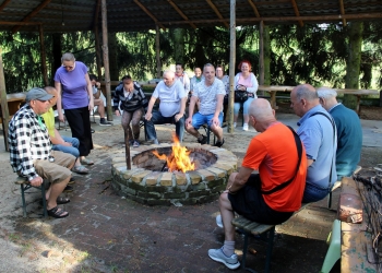 Spotkanie przy ognisku, uczestnicy siedzą dookoła ogniska.