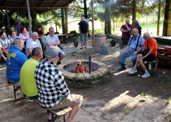 Spotkanie przy ognisku, uczestnicy siedzą dookoła ogniska.