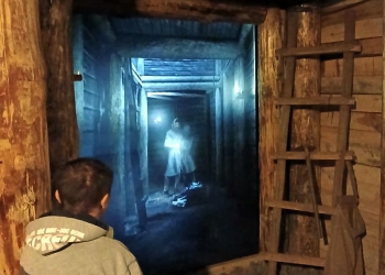 Uczestnik ogląda podświetlana ekspozycję przedstawiającą górnika podczas pracy.