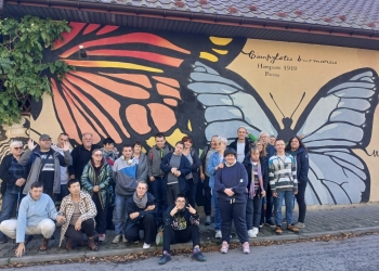 Wspólna fotografia całej grupy na tle muralu przedstawiającego motyla.
