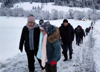 Uczestnicy wycieczki podczas spaceru. Droga prowadzi pod górę, jest biała od śniegu.