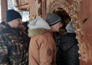 Kilka osób wchodzi przez niskie, drewniane drzwi do chałupy Gasieniców.