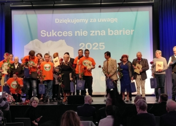 Wspólna fotografia osób wyróżnionych w konkursie. Uczestnicy stoją na scenie. W tle baner nawiązujący tematycznie do tresci konkursu.