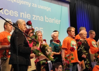 Wspólna fotografia osób wyróżnionych w konkursie. Uczestnicy stoją na scenie. W tle baner nawiązujący tematycznie do tresci konkursu.