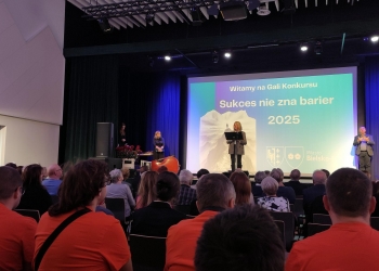 Dyrektor Domu Kultury pani Małgorzata Motyka-Madej przemawia stojąc na scenie. W tle znajduje się baner nawiązujący do treści konkursu.