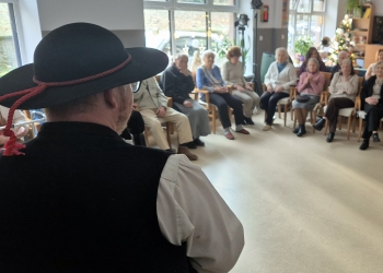 Wspólne kolędowanie. Na pierwszym planie członek kapeli, na głowie ma góralski kapelusz.