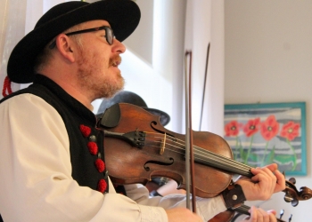 Mężczyzna w stroju ludowym gra na skrzypcach.