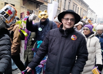 Zdjęcie przedstawia osoby biorące udział w barwnym pochodzie. Jedna z osób na na twarzy maskę kota, inna ma na głowie góralski kapelusz.