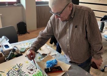 Na zdjęciu są osoby malujące obraz drzewa.