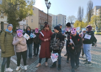 Na zdjęciu znajdują się osoby świętujące Światowy Dzień Świadomości Autyzmu. W rękach trzymają rekwizyty nawiązujące do tematyki wydarzenia.