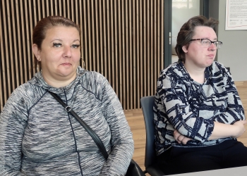Dwie osoby pozują do fotografii siedząc przy stole.
