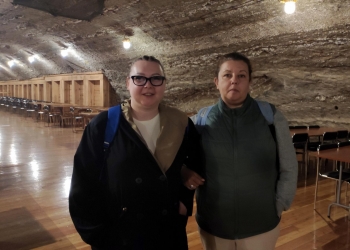 Dwie osoby pozują do zdjęcia w sali rekreacyjnej.