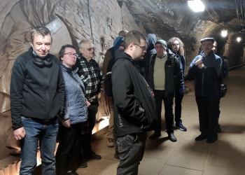 Zwiedzanie korytarzy kopalnianych. Grupa zwiedzających słucha opowiadania przewodnika.
